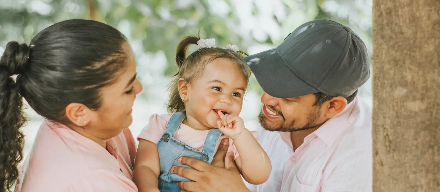 Parents laughing with their young daughter outdoors
