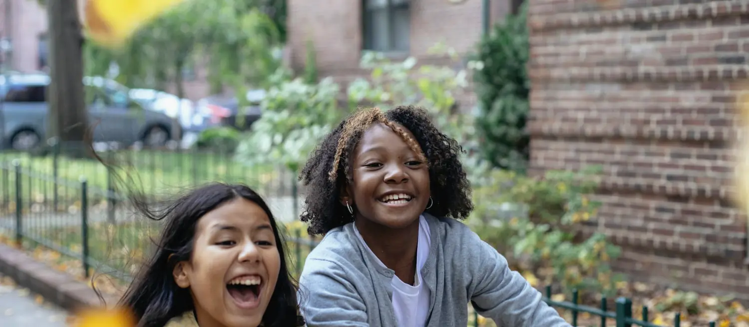 Two girls laughing together on an autumn street