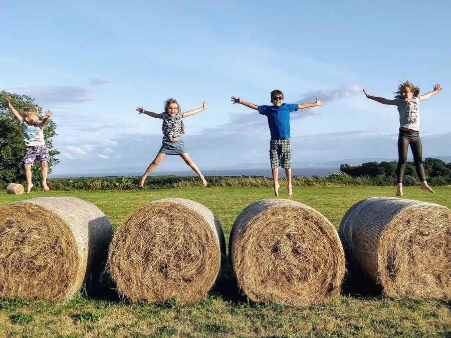 Children jumping with their arms out under a wide open sky