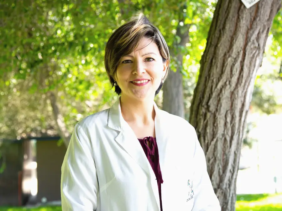 A researcher in a white coat smiling outdoors
